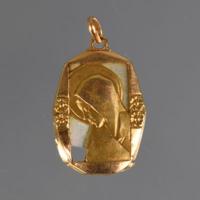 an image of a gold pendant with a picture of a woman holding a knife