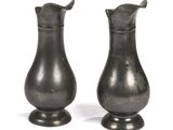 two silver vases sitting next to each other on a white surface