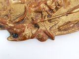 a close up of a gold plate with a fish on it