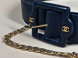 a blue belt with a gold chain on a white surface
