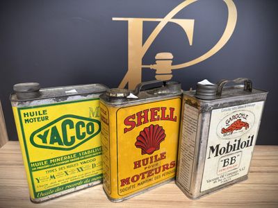 three vintage shell oil cans sitting on top of a wooden table
