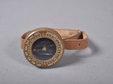 une montre avec un bracelet en cuir posée sur un fond blanc