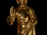a gold statue of a man with a hand in his right hand