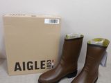 une paire de bottes en cuir marron posée sur une table, à côté d'une boîte