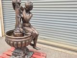 a bronze statue of a boy and a girl sitting on a fountain