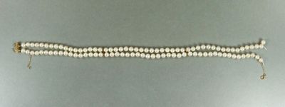 un gros plan d'un bracelet en perles blanches posé sur une surface grise
