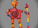 brightly colored clay figurine of a man with a staff