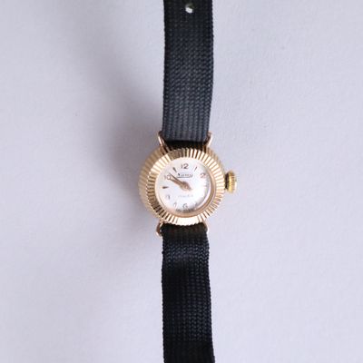 a gold watch with a black band on a white surface