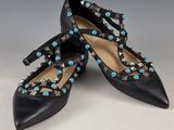 une paire de chaussures en cuir noir ornées de pierres turquoise sur les orteils