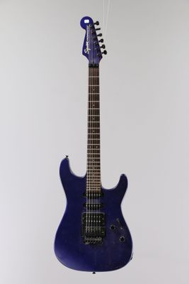 an electric guitar hanging from a string on a white wall