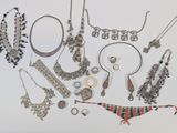 many different necklaces and bracelets laid out on a white surface