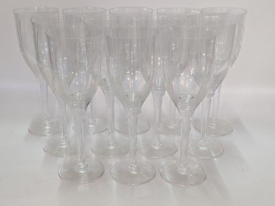 six verres à vin transparents sont alignés sur une surface blanche