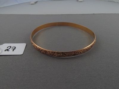 un bracelet en or posé sur une table, à côté d'une étiquette de prix