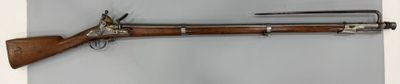 un vieux fusil accroché au mur à côté d'un couteau
