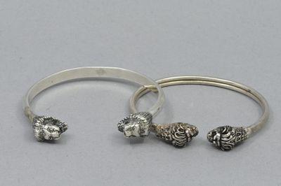deux bracelets en argent et une bague en argent posés sur une surface blanche