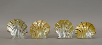 three glass figurines of leaves on a white surface