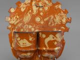 an orange and white vase sitting on top of a metal stand