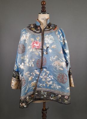 une photo d'une veste bleue ornée de fleurs, posée sur un mannequin