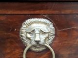 a wooden drawer with a lion head handle on it
