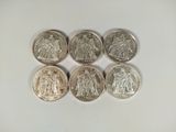 six different british coins are arranged in a row on a white surface