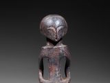 an old wooden figurine of a man with a bird on his head
