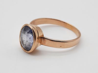 gros plan d'une bague en or avec une pierre bleue