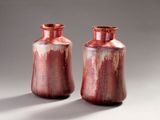 pair of red vases sitting on top of a white table