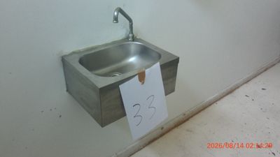 a sink in the corner of a bathroom with a note attached to it