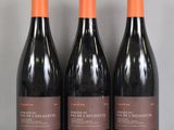 trois bouteilles de vin rouge sont posées sur une table en verre