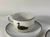 two cups and saucers with a bird painted on them