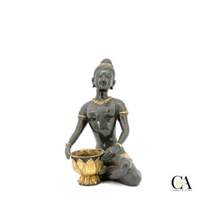 une statue représentant une femme assise par terre avec un bol