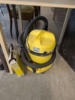 un aspirateur jaune posé par terre à côté d'une table
