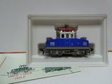 un petit train bleu dans une boîte blanche posée sur une table