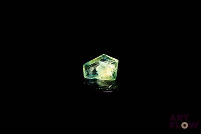 a close up of a green diamond on a black surface