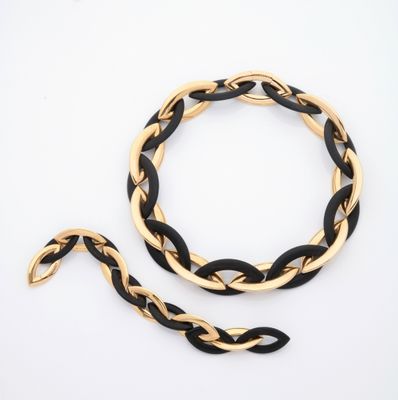 un gros plan sur un bracelet noir et doré et une chaîne dorée