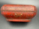 an old red box with a floral design on the lid