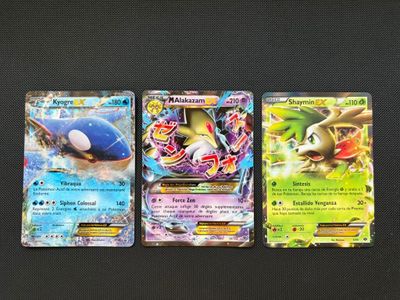 three pokemon cards are lined up on a black surface