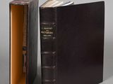 un livre ouvert posé sur une table, à côté d'un livre fermé