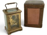 a small clock sitting next to a box on a white surface