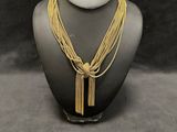 a gold necklace with a tassel on a mannequin neck