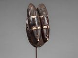 a wooden mask with two faces on a stand