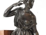 bronze statue of a woman sitting on top of a wooden block