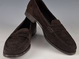 une paire de chaussures en daim marron posées sur une surface blanche