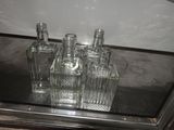 four empty glass bottles sitting on a glass shelf