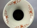 a white vase with orange designs on it on a gray surface