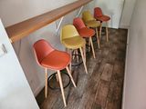 Des tabourets de bar aux couleurs vives sont alignés contre un mur dans une cuisine