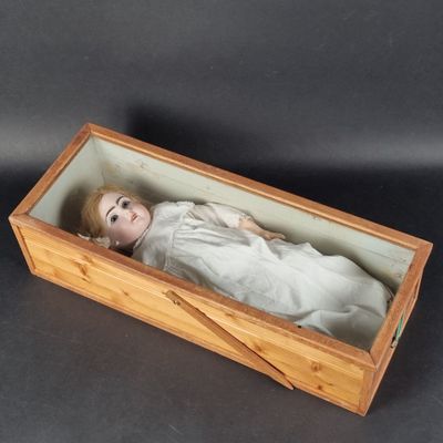 a small doll in a wooden box on a table