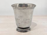 a silver cup on a wooden table with a white wall in the background