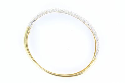 un gros plan d'un bracelet rigide en or et diamants sur fond blanc