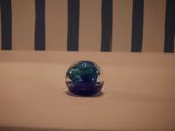 a blue and green ball sitting on top of a bed